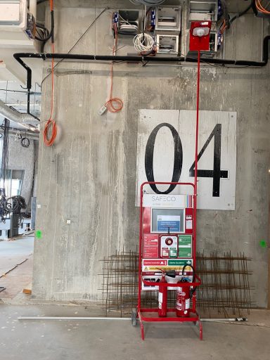 Équipement de chantier rouge sur un mur avec le numéro 04, câbles suspendus au-dessus.
